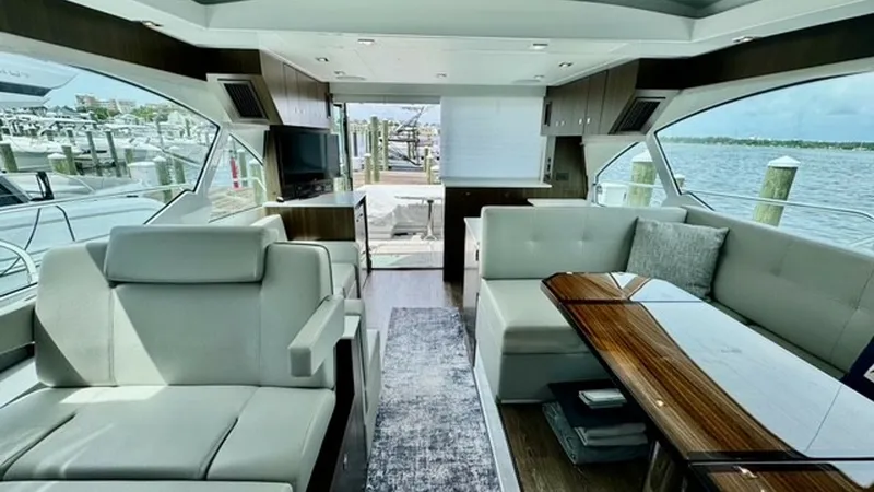 Slide: The Image of Spacious Salon with Panoramic Views The salon of the 2023 Cruisers Yachts 50 Cantius offers a luxurious and open atmosphere, featuring plush seating and a sleek, modern design. Large windows provide stunning panoramic views and ample natural light, enhancing the elegant wood finishes and st - 6489138
