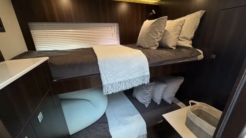 Slide: The Image of Cozy Twin Bunk Cabin This inviting twin bunk cabin offers a warm and intimate space, with sleek dark wood finishes and soft ambient lighting. The comfortable beds are complemented by modern bedding and a practical layout, ensuring a restful experience. Ample storage and styli - 6489155