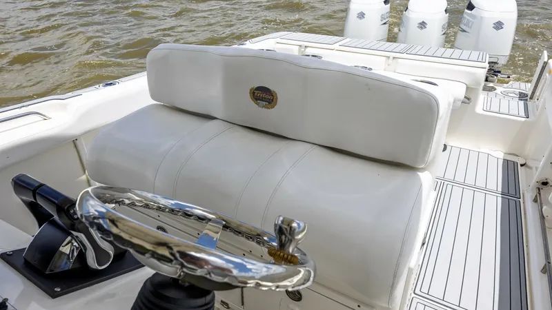 Slide: The Image of Helm Station with Triple Outboards The helm station of the 2005 Triton 351 Center Console features a robust steering wheel and sleek controls, offering precise navigation. The comfortable cushioned seating provides excellent support for long voyages. Beyond the helm, three powerful outboar - 6687480