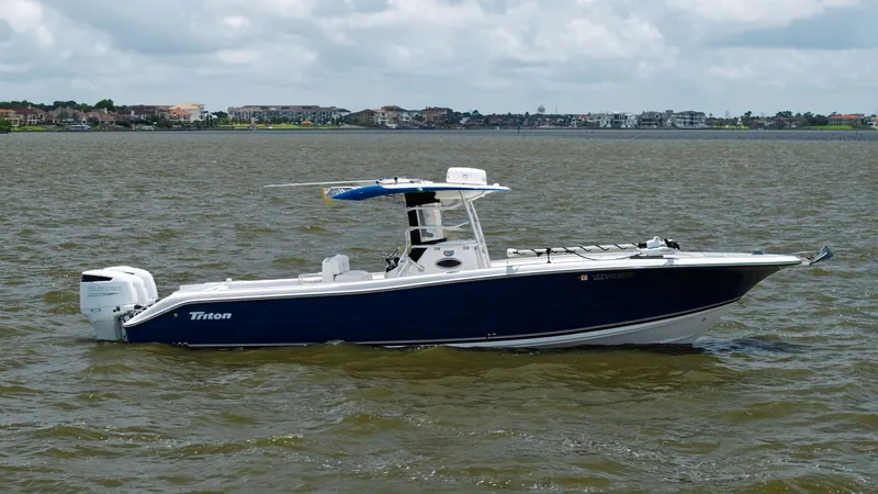 The Image of Side Profile of Triton 351 Center Console This image showcases the sleek side profile of the 2005 Triton 351 Center Console. The vessel features a striking blue hull with a crisp white deck, complemented by a sturdy T-top providing ample shade. Twin outboard engines ensure powerful performance, m - 6687453