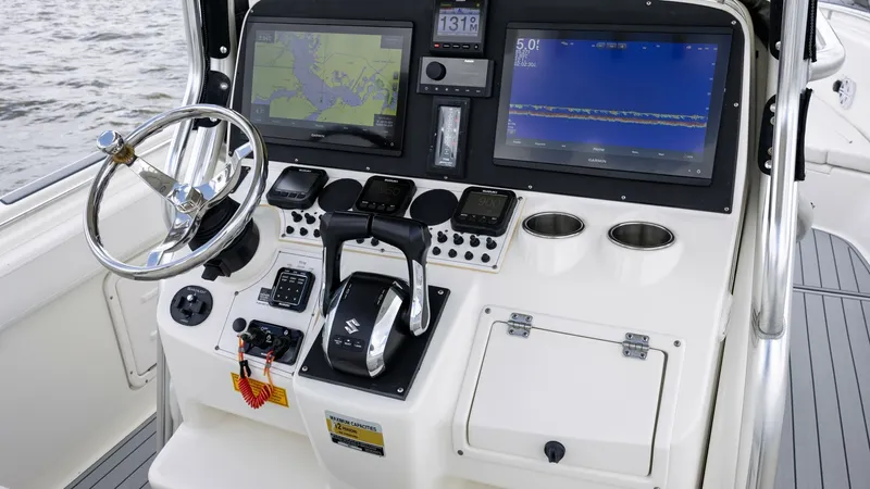 Slide: The Image of Helm Station with Dual Displays The helm station of the 2005 Triton 351 Center Console features dual electronic displays for navigation and system monitoring. The ergonomic layout includes a stainless steel steering wheel, throttle controls, and easy access to essential switches. Ample - 6687458