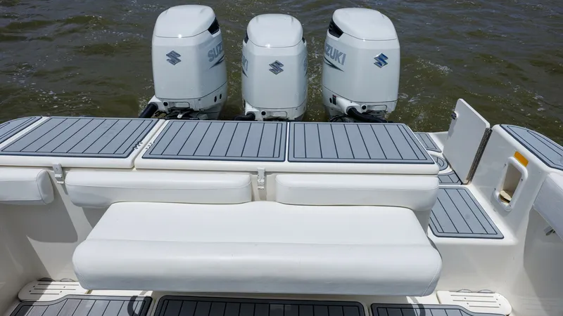 Slide: The Image of Aft Deck with Triple Outboards This view captures the spacious aft deck of the 2005 Triton 351 Center Console, featuring three powerful Suzuki outboard engines. The deck is equipped with sleek, non-slip flooring and a comfortable bench seat, ideal for fishing or relaxing. The layout pr - 6687467