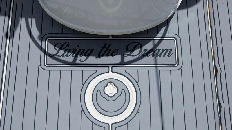 Slide: The Image of Custom Deck with Logo Detail The deck of the 2005 Triton 351 Center Console features a custom design with the phrase 'Living the Dream' prominently displayed. This detail enhances the boat's aesthetic appeal and adds a personal touch. The sleek, non-slip surface ensures safety and st - 6687468