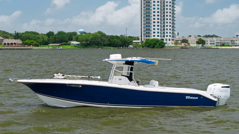 Slide: The Image of Side Profile of Triton 351 Center Console This 2005 Triton 351 Center Console showcases a sleek, deep-V hull designed for optimal performance and stability. The rich blue exterior is complemented by a spacious, open deck layout, ideal for fishing and leisure activities. A sturdy T-top provides sh - 6687495