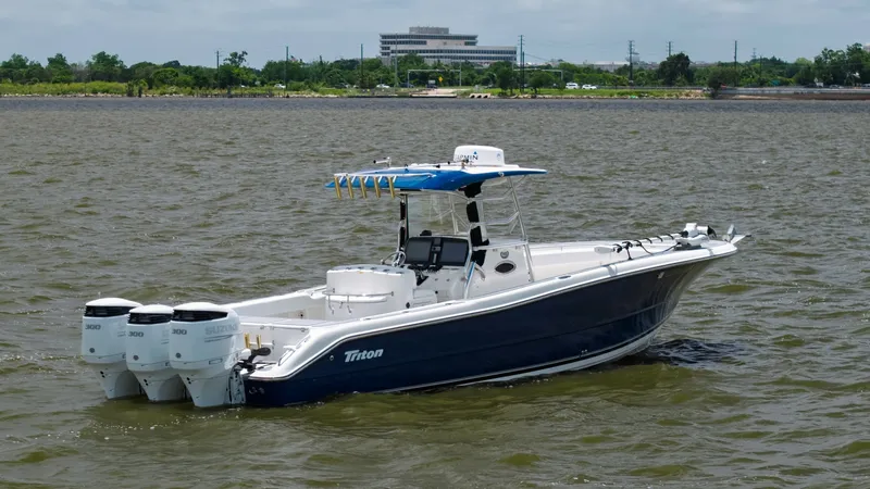 Slide: The Image of Side View of Triton 351 Center Console This image showcases the sleek design of the 2005 Triton 351 Center Console, featuring a striking blue hull and spacious deck layout. Equipped with three powerful outboard engines, this vessel promises exceptional performance and speed on the water. The T - 6687493