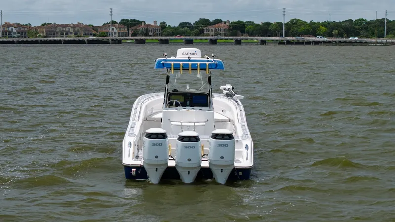 Slide: The Image of Aft View with Triple Outboards This image showcases the aft view of the 2005 Triton 351 Center Console, highlighting its powerful triple 300 horsepower outboard engines. The spacious deck is designed for both fishing and cruising, offering ample space for activities. The sleek lines an - 6687494