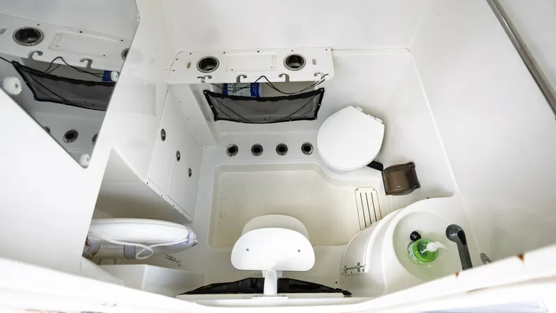Slide: The Image of Compact Marine Head Compartment This image showcases the well-organized head compartment of the 2005 Triton 351 Center Console. The space-efficient design includes a toilet, sink, and practical storage options, ensuring comfort and convenience on extended trips. Durable materials and cl - 6687486