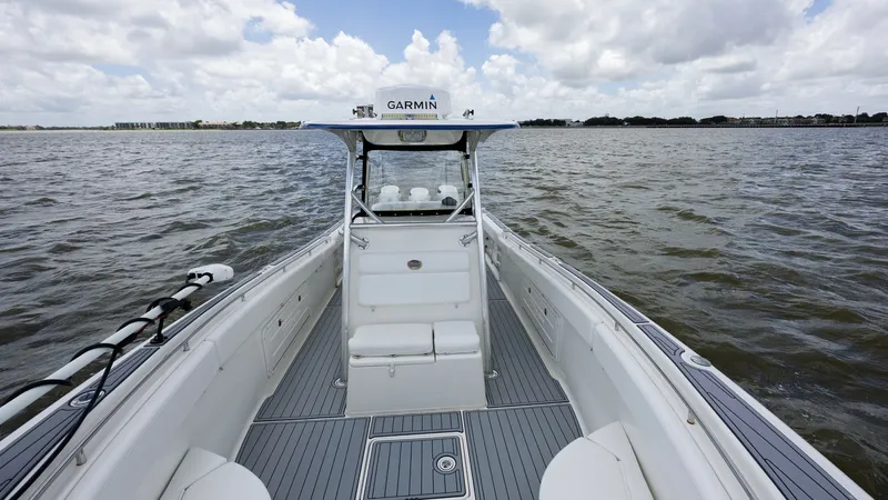 Slide: The Image of Forward Deck with Helm View This image showcases the spacious forward deck of the 2005 Triton 351 Center Console. The area features sleek, non-slip decking and ample seating, ideal for relaxation or fishing. The helm is equipped with advanced Garmin navigation, ensuring a smooth and - 6687474
