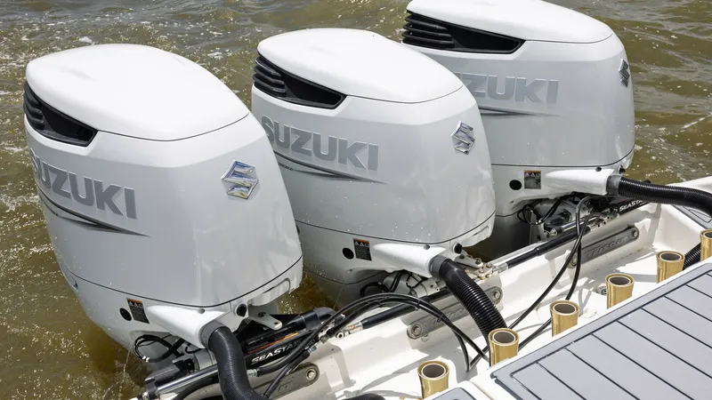 Slide: The Image of Triple Suzuki Outboard Engines This image showcases the powerful triple Suzuki outboard engines on the 2005 Triton 351 Center Console. These engines offer exceptional performance and reliability, ideal for high-speed cruising and offshore fishing. The sleek, modern design of the motors - 6687484