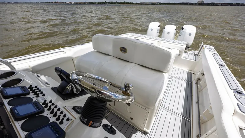 Slide: The Image of Helm and Aft Deck View This image showcases the helm and aft deck of the 2005 Triton 351 Center Console. The helm features a sleek, modern design with multiple navigation displays and a polished steering wheel for precise control. The spacious aft deck offers ample seating and - 6687481