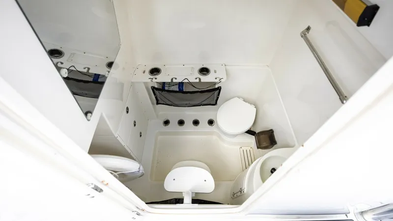 Slide: The Image of Enclosed Head Compartment The 2005 Triton 351 Center Console features a compact yet functional enclosed head compartment. This space is equipped with essential amenities, including a marine toilet and a small sink, providing convenience for extended trips. The clean, white finish - 6687487