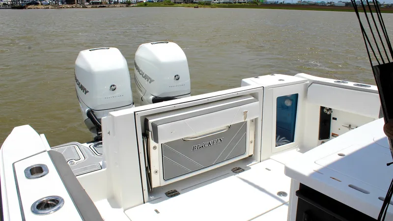Slide: The Image of Aft Fishing Station with Engines The aft section of the Blackfin 332 Center Console showcases a well-equipped fishing station with easy access to the dual Mercury outboard engines. The spacious deck is designed for functionality, featuring robust storage compartments and a sleek, integra - 6687439