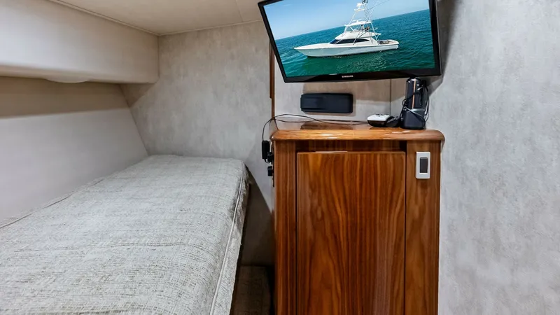 Slide: The Image of Guest Cabin with Entertainment System This cozy guest cabin on the 2018 Viking 62 Convertible features a comfortable single berth with plush bedding. The warm wood cabinetry adds a touch of elegance, complementing the neutral wall tones. A mounted flat-screen TV provides entertainment, making - 8440065