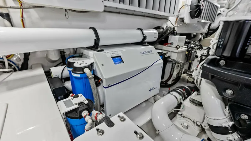 Slide: The Image of Engine Room with Advanced Equipment This image showcases the meticulously organized engine room of the 2018 Viking 62 Convertible. The space is equipped with state-of-the-art machinery, including an AquaMatic watermaker and robust piping systems, ensuring optimal performance and reliability - 8440097