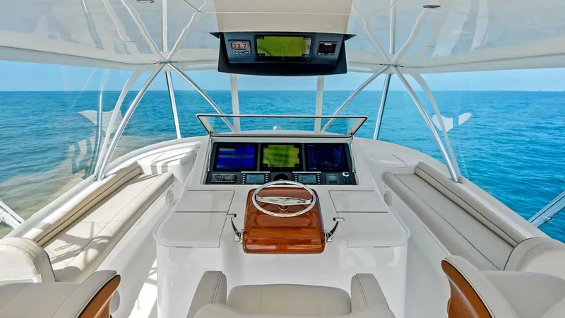 Slide: The Image of Flybridge Helm with Panoramic Views The flybridge helm of the 2018 Viking 62 Convertible, 'Rollin' Deep,' offers a commanding view of the open sea. Equipped with state-of-the-art navigation systems, the helm features a polished wood steering wheel and spacious seating for optimal comfort. T - 8440031