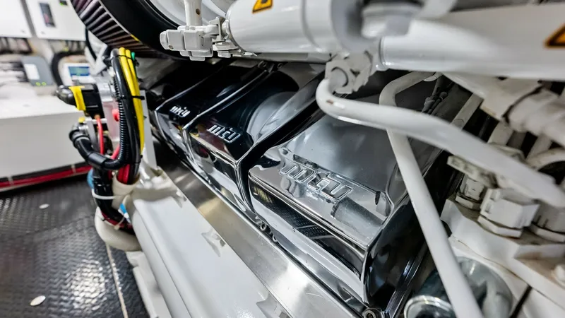 Slide: The Image of Engine Room with MTU Engines This image showcases the meticulously maintained engine room of the 2018 Viking 62 Convertible, featuring powerful MTU engines. The clean and organized layout highlights the vessel's commitment to performance and reliability, with polished surfaces and ex - 8440092