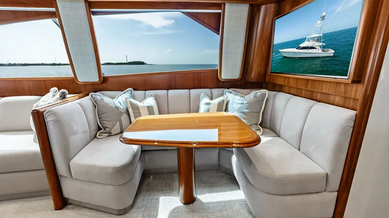 Slide: The Image of Salon Dinette with Panoramic Views This inviting salon dinette on the 2018 Viking 62 Convertible features plush, curved seating with elegant upholstery, perfect for relaxed dining or entertaining. The richly finished wood table complements the warm wood paneling, creating a cozy yet upscal - 8440043
