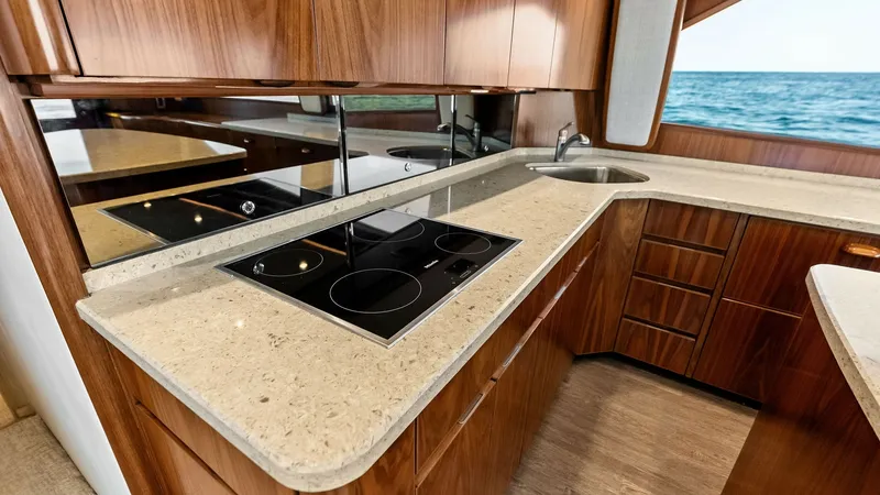 Slide: The Image of Galley with Modern Appliances The galley of the 2018 Viking 62 Convertible showcases sleek, high-gloss wood cabinetry and polished stone countertops. Equipped with modern appliances, including an electric cooktop, this space combines functionality with elegance. The large windows prov - 8440040