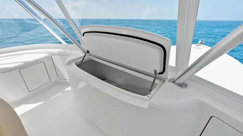 Slide: The Image of Flybridge Storage Compartment Open View The image showcases an open storage compartment on the flybridge of the 2018 Viking 62 Convertible. This spacious compartment offers easy access and ample storage, ideal for keeping essentials secure and organized during voyages. The sleek white finish co - 8440082