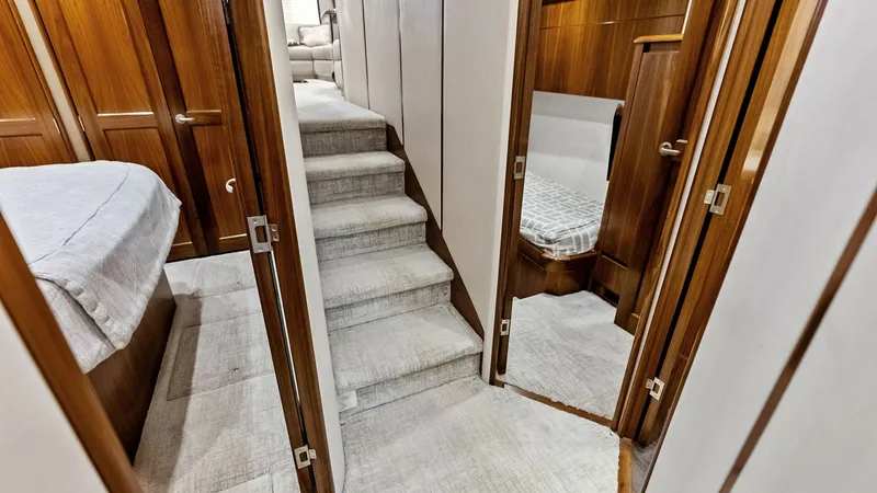 Slide: The Image of Lower Deck Corridor and Cabins This image showcases the elegant lower deck corridor of the 2018 Viking 62 Convertible, featuring rich wooden finishes and plush carpeting. The layout includes access to multiple staterooms, each with finely crafted doors and discreet lighting, creating a - 8440045