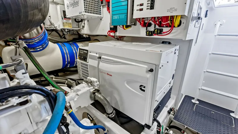 Slide: The Image of Engine Room with Generator System The engine room features a meticulously organized layout with a prominent Cummins Onan generator, ensuring reliable power supply on the water. High-quality components and neatly arranged wiring contribute to the room's efficient functionality. The space i - 8440089