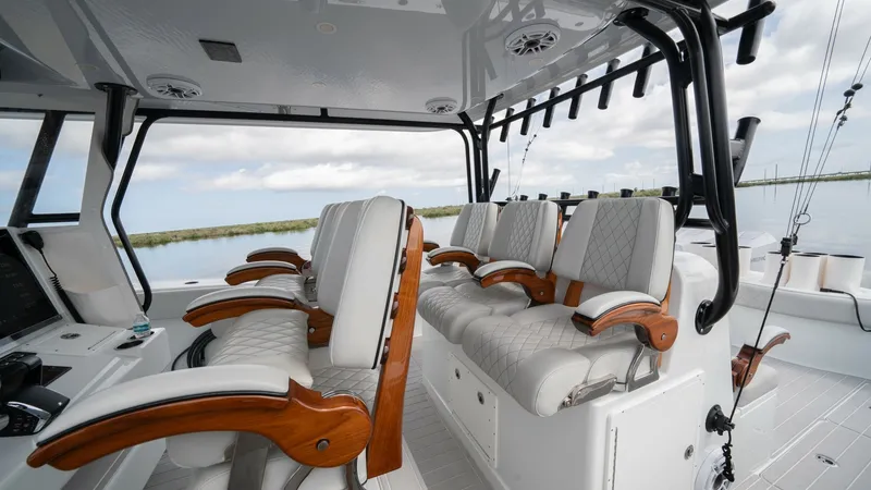 Slide: The Image of Helm Seating and Console Area The helm area of the Freeman 42 LR features luxurious seating with plush, diamond-stitched upholstery and elegant wooden armrests. The spacious layout ensures comfort and accessibility, complemented by state-of-the-art navigation equipment. Overhead, a st - 6725104