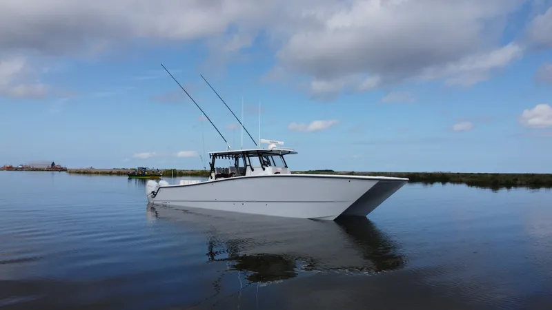 Slide: The Image of Side Profile on Open Water The Freeman 42 LR 'Fortunate Son' glides elegantly across calm waters, showcasing its sleek and robust design. The side profile highlights the vessel's streamlined hull, perfect for efficient and smooth navigation. With fishing rods mounted on the hardtop - 6725121