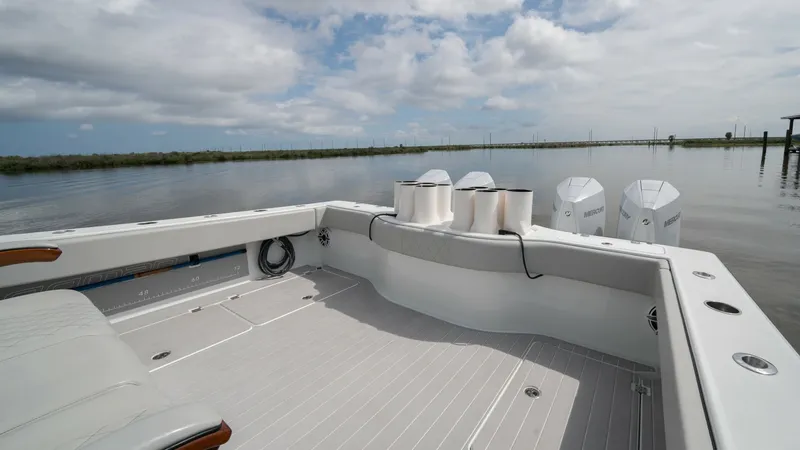 Slide: The Image of Spacious Aft Deck with Engines The aft deck of the 2023 Freeman 42 LR 'Fortunate Son' offers ample space for leisure and fishing activities. It features sleek, non-slip flooring and comfortable seating with wooden accents, providing both style and functionality. The powerful outboard e - 6725113