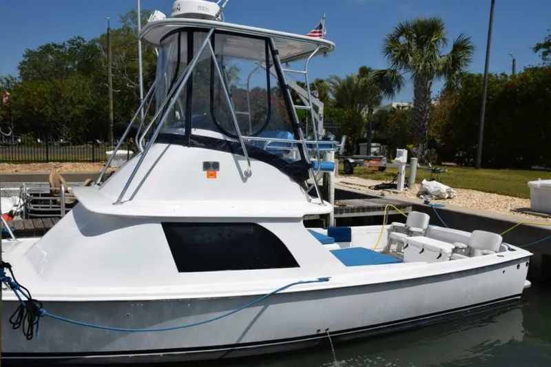 Slide: The Image of 1976 Bertram Flybridge Cruiser docked, featuring sleek design and spacious deck under clear blue sky - 7384095