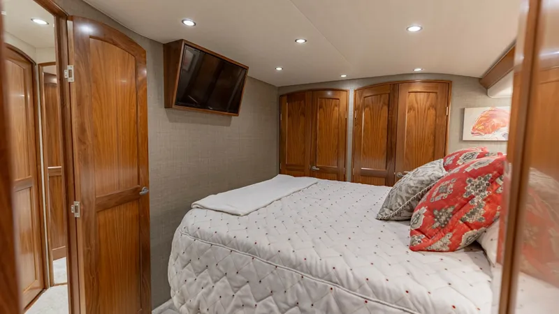 Slide: The Image of Guest Stateroom with Ensuite This cozy guest stateroom on the 2020 Viking 62 Convertible features a plush double bed adorned with elegant bedding and accent pillows, providing comfort and style. The space is enhanced by rich wood cabinetry, offering ample storage, and a wall-mounted - 6711678