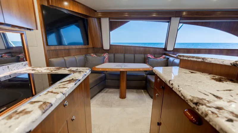 Slide: The Image of Spacious Salon with Ocean Views This elegant salon aboard the 2020 Viking 62 Convertible offers a luxurious and comfortable seating area with a rich wood finish and plush L-shaped sofa. Large panoramic windows provide stunning ocean views, enhancing the sense of openness and light. The - 6711671