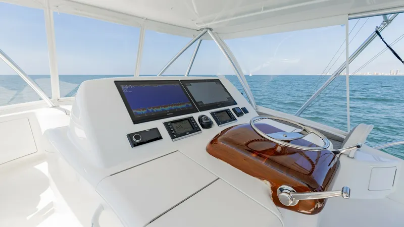 Slide: The Image of Flybridge Helm Station with Electronics This image showcases the helm station on the flybridge of the 2020 Viking 62 Convertible. The station features dual multifunction displays, providing advanced navigation and system monitoring. The polished wooden steering wheel and stainless-steel accents - 6711695
