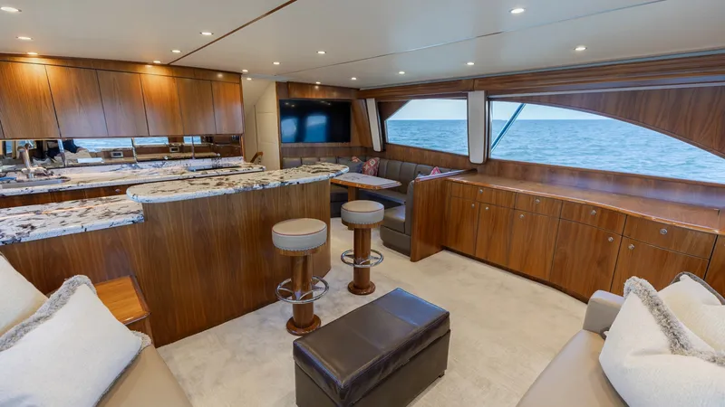 Slide: The Image of Luxurious Salon with Ocean Views This elegant salon aboard the 2020 Viking 62 Convertible showcases exquisite wood finishes and plush seating. The open layout features a granite-topped bar with stylish stools, creating a perfect space for entertaining. Large windows offer stunning ocean - 6711668