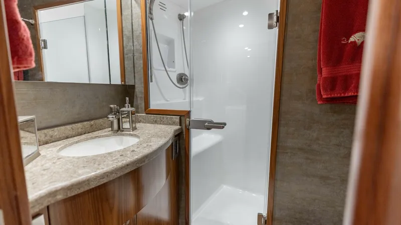 Slide: The Image of Luxurious Guest Bathroom This elegantly designed guest bathroom on the 2020 Viking 62 Convertible features a spacious shower with a glass door, offering a modern and clean aesthetic. The vanity is adorned with a polished stone countertop and sleek fixtures, enhancing the sense of - 6711681