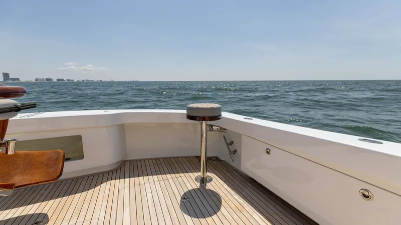 Slide: The Image of Spacious Aft Deck with Ocean View The aft deck of the 2020 Viking 62 Convertible offers a stunning ocean vista, perfect for relaxation or fishing. The teak flooring adds a touch of elegance, while the built-in seating and mounted barstool provide comfort and functionality. This area is id - 6711699