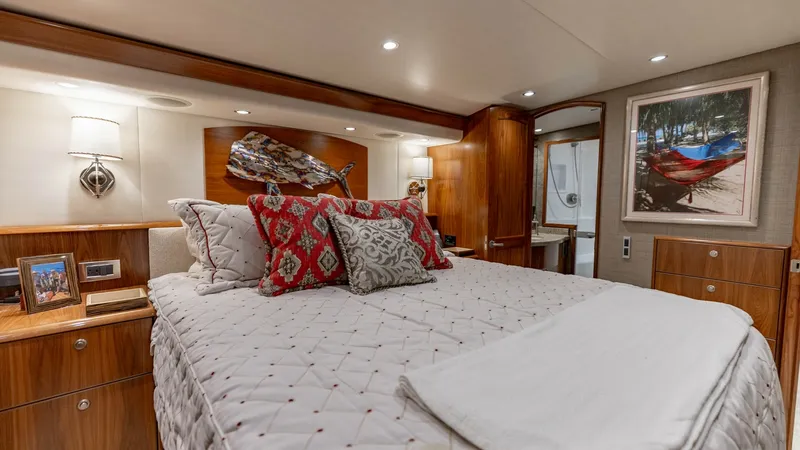 Slide: The Image of Luxurious Master Stateroom This elegant master stateroom aboard the 2020 Viking 62 Convertible features a plush, queen-sized bed adorned with designer pillows. Warm wood finishes and recessed lighting create a cozy and inviting atmosphere, complemented by stylish artwork and modern - 6711675