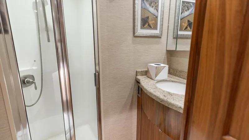 Slide: The Image of Luxurious Ensuite Head This elegant ensuite head on the 2020 Viking 62 Convertible features a sleek glass-enclosed shower and a stylish vanity with a polished granite countertop. The rich wood cabinetry adds a touch of luxury, complemented by contemporary wall art. Modern fixtu - 6711691