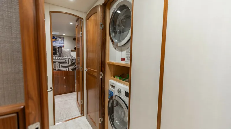 Slide: The Image of Laundry Area with Washer and Dryer This image features the efficient laundry area aboard the 2020 Viking 62 Convertible. The space is equipped with a stacked washer and dryer, neatly enclosed behind elegant wooden cabinetry. The area is designed for convenience, seamlessly blending functio - 6711688