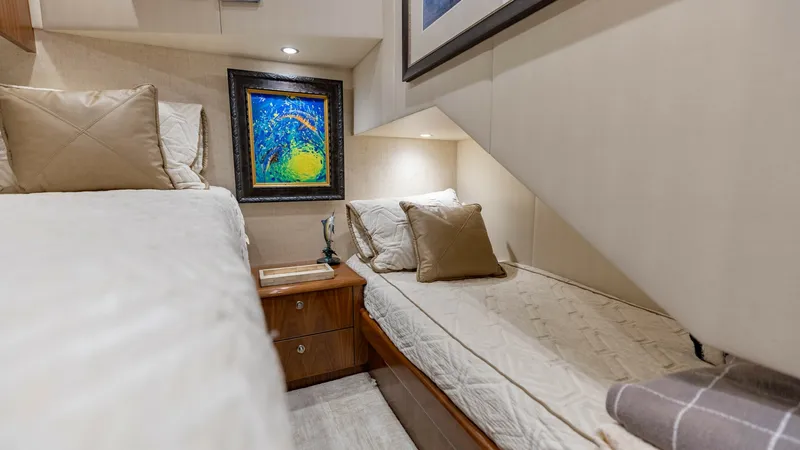 Slide: The Image of Guest Stateroom with Twin Beds This inviting guest stateroom on the 2020 Viking 62 Convertible features cozy twin beds, perfect for accommodating additional guests. The space is beautifully appointed with soft, neutral tones and accented by elegant artwork, creating a warm and welcomin - 6711683