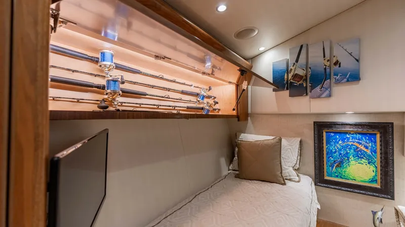 Slide: The Image of Guest Stateroom with Rod Storage This cozy guest stateroom on the Viking 62 Convertible features a comfortable single berth adorned with plush bedding. The overhead rod storage is elegantly illuminated, showcasing high-quality fishing equipment. Nautical artwork and soft ambient lighting - 6711684