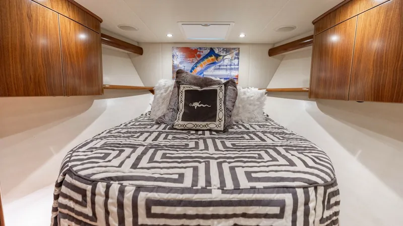 Slide: The Image of Luxurious Forward Stateroom This elegant forward stateroom in the 2020 Viking 62 Convertible features a spacious island bed with stylish geometric bedding. Rich wood cabinetry provides ample storage, while recessed lighting creates a warm and inviting atmosphere. The artistic decor - 6711689