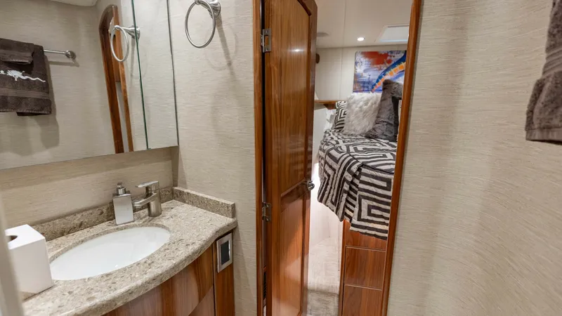 Slide: The Image of Guest Cabin and Ensuite This image showcases the guest cabin with an adjoining ensuite on the Viking 62 Convertible. The cabin features a plush bed adorned with stylish bedding, complemented by warm wood finishes. The ensuite is elegantly designed, offering a sleek vanity with a - 6711692