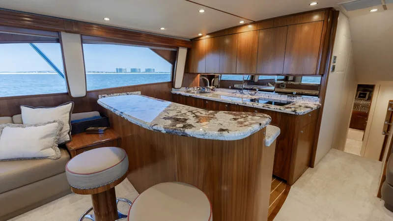 Slide: The Image of Galley and Lounge Area This elegant galley on the 2020 Viking 62 Convertible features high-gloss cabinetry and a striking marble countertop, offering both style and functionality. The open layout seamlessly connects to the plush lounge area, complete with comfortable seating an - 6711669