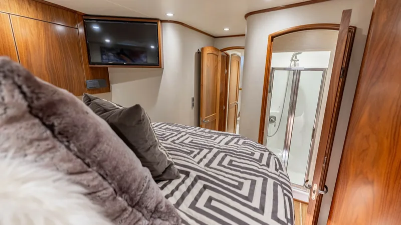 Slide: The Image of Luxurious Stateroom with En Suite This elegant stateroom aboard the 2020 Viking 62 Convertible features a plush bed adorned with stylish patterned linens and plush pillows, creating a cozy retreat. Warm wood finishes and soft ambient lighting enhance the sophisticated atmosphere. The en s - 6711690