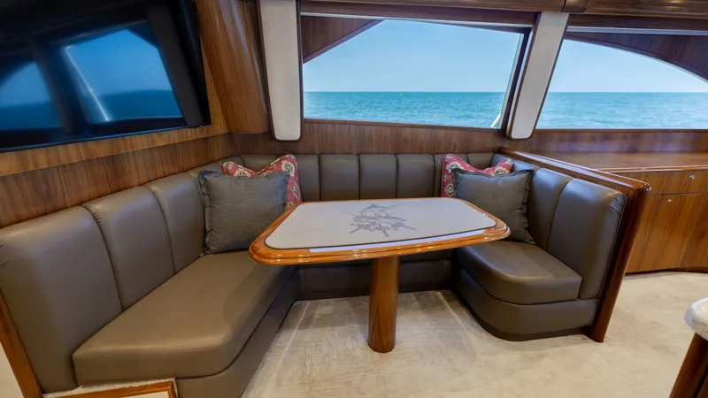 Slide: The Image of Elegant Salon Dinette Area This inviting salon dinette on the 2020 Viking 62 Convertible features plush, curved seating with luxurious leather upholstery and a beautifully crafted wooden table. Large windows provide an expansive view of the ocean, creating a serene dining atmospher - 6711672