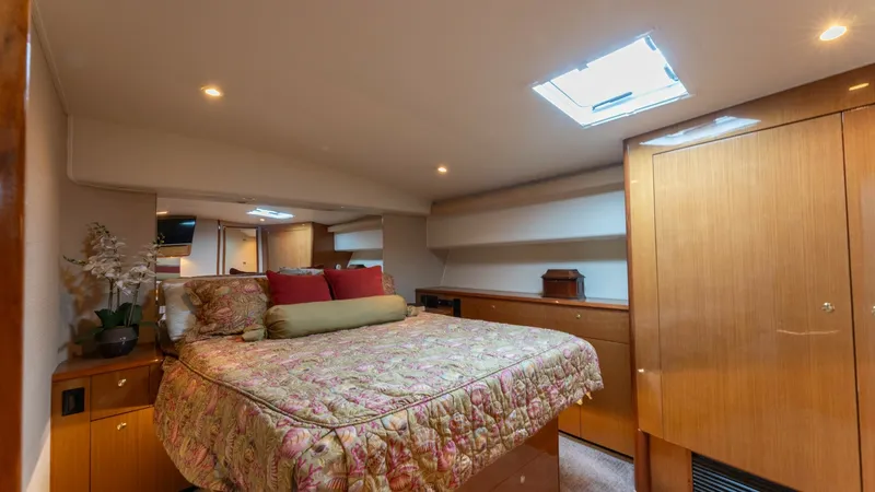 Slide: The Image of Master Stateroom with Skylight The master stateroom of the 2001 Viking 65 Enclosed Bridge offers a spacious and inviting retreat. It features a large, comfortable bed accented by elegant wood cabinetry and soft lighting. A skylight above provides natural light, enhancing the warm and c - 6767179