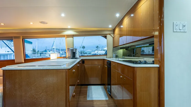 Slide: The Image of Galley with Ample Counter Space The galley of the 2001 Viking 65 Enclosed Bridge offers a spacious and functional layout, featuring elegant wooden cabinetry and sleek countertops. Natural light floods the space through expansive windows, enhancing the warm tones of the wood. Modern appl - 6767166