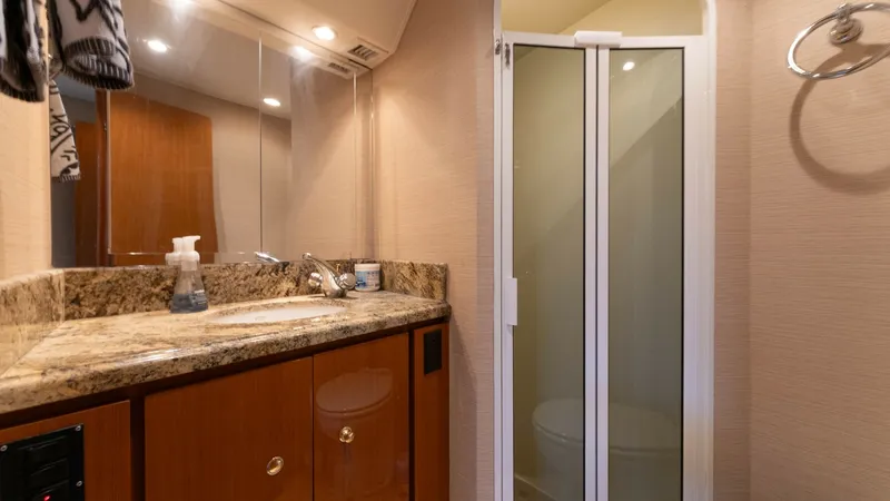 Slide: The Image of Elegant En-Suite Bathroom This en-suite bathroom features a luxurious granite countertop and sleek wooden cabinetry, offering ample storage space. The well-lit mirror enhances the vanity area, while the enclosed shower provides privacy and convenience. Elegant fixtures and a taste - 6767178