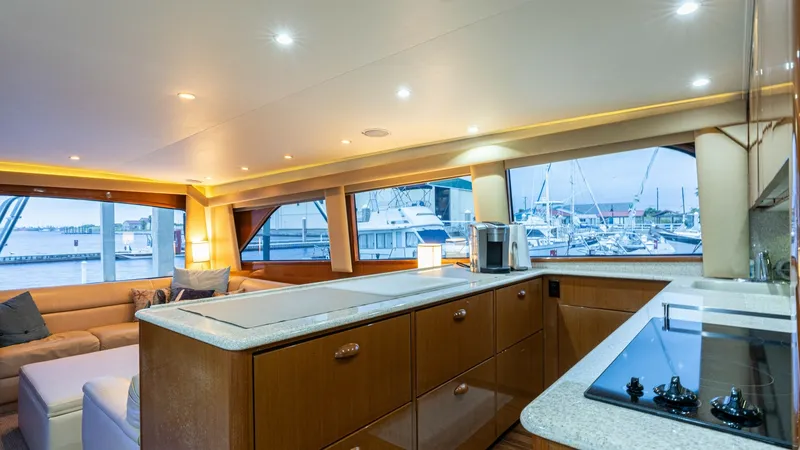 Slide: The Image of Spacious Galley with Marina Views The galley on the Viking 65 Enclosed Bridge yacht offers a blend of functionality and elegance, featuring sleek countertops and ample cabinetry for storage. Large windows provide stunning views of the marina, enhancing the open and inviting atmosphere. Th - 6767167