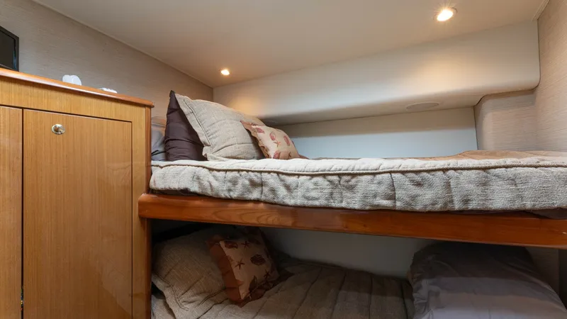 Slide: The Image of Cozy Twin Bunk Cabin This inviting cabin on the 2001 Viking 65 Enclosed Bridge features twin bunks, providing a comfortable space for guests. The warm wood cabinetry and soft lighting create a cozy atmosphere, while the efficient layout maximizes space. Ideal for relaxing aft - 6767176